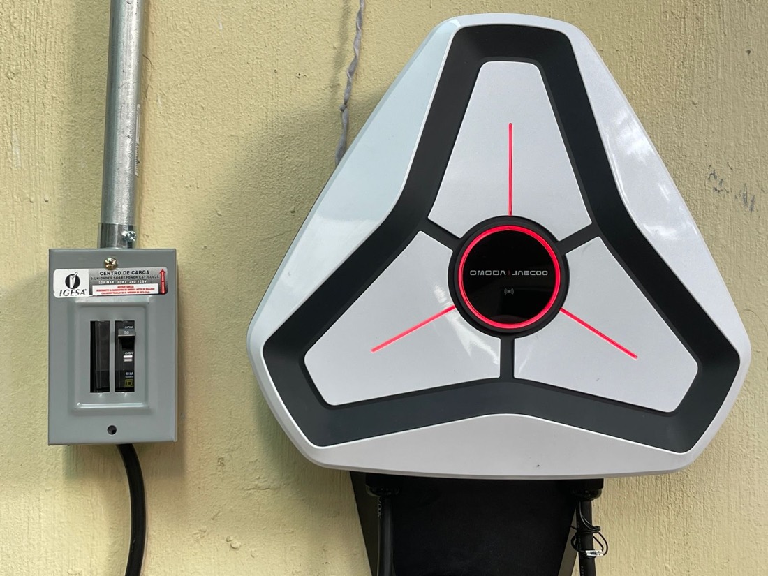 Cargador para auto eléctrico instalado en una pared, conectado a un vehículo